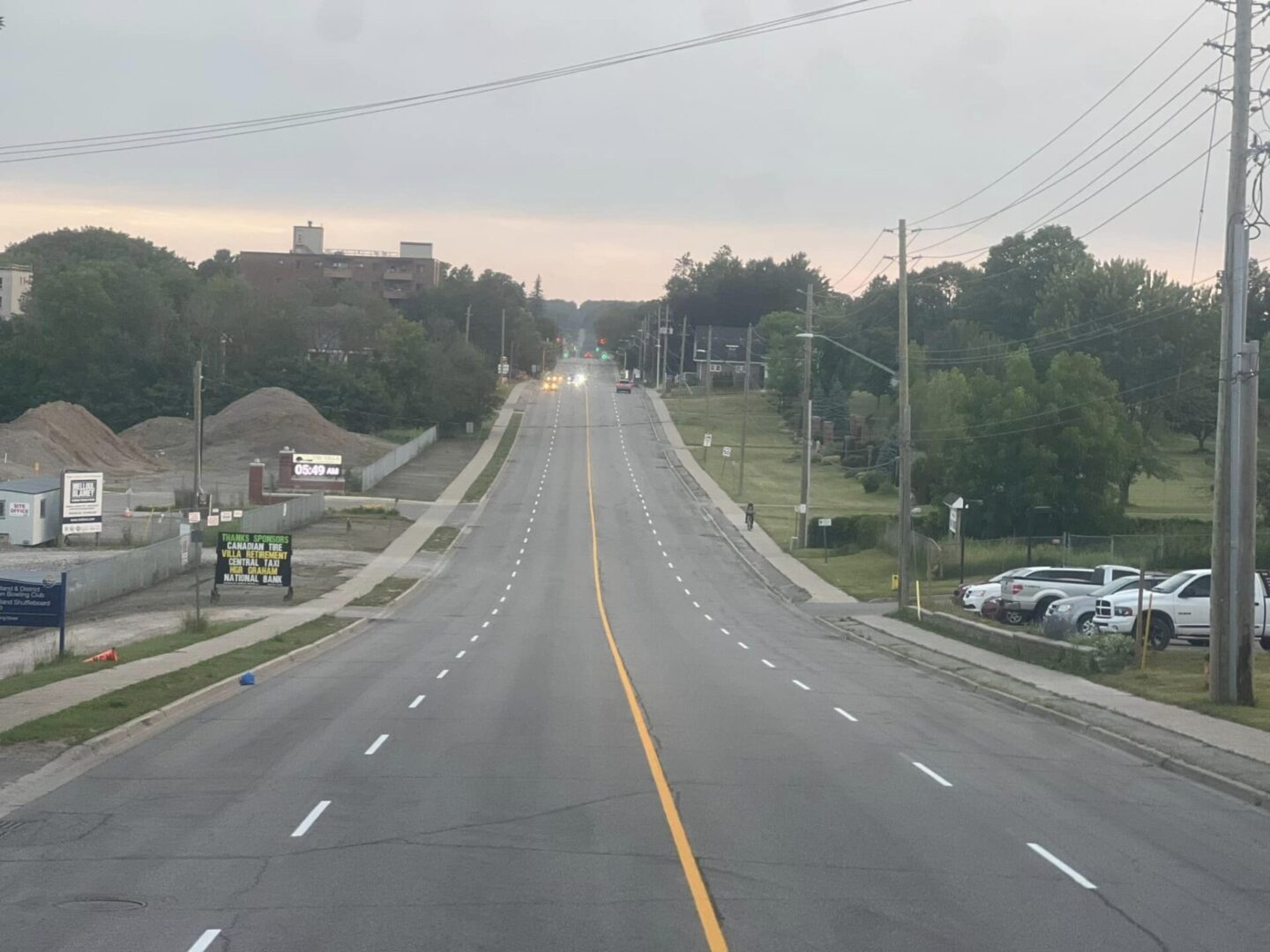 A long highway with cars parked on the side